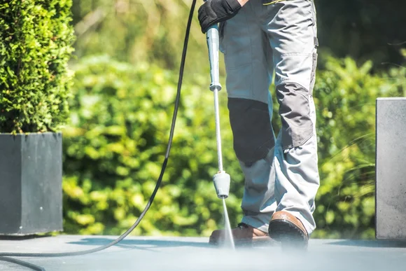 Person reinigt Terrasse mit Hochdruckreiniger